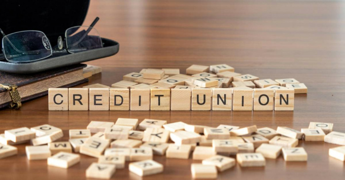 A row of small wooden letter blocks that spell out the words credit union. There are other letter blocks scattered around.