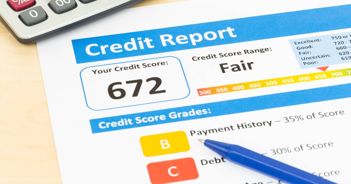 A close-up of a credit report showing a credit score of 672. There are a calculator and pen near the report.